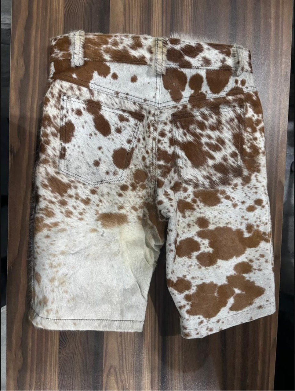Brown and white cowhide leather shorts for men with raw finish and unique fur layout—perfect for outdoor events, cowboy fashion, or eye-catching casual outfits.