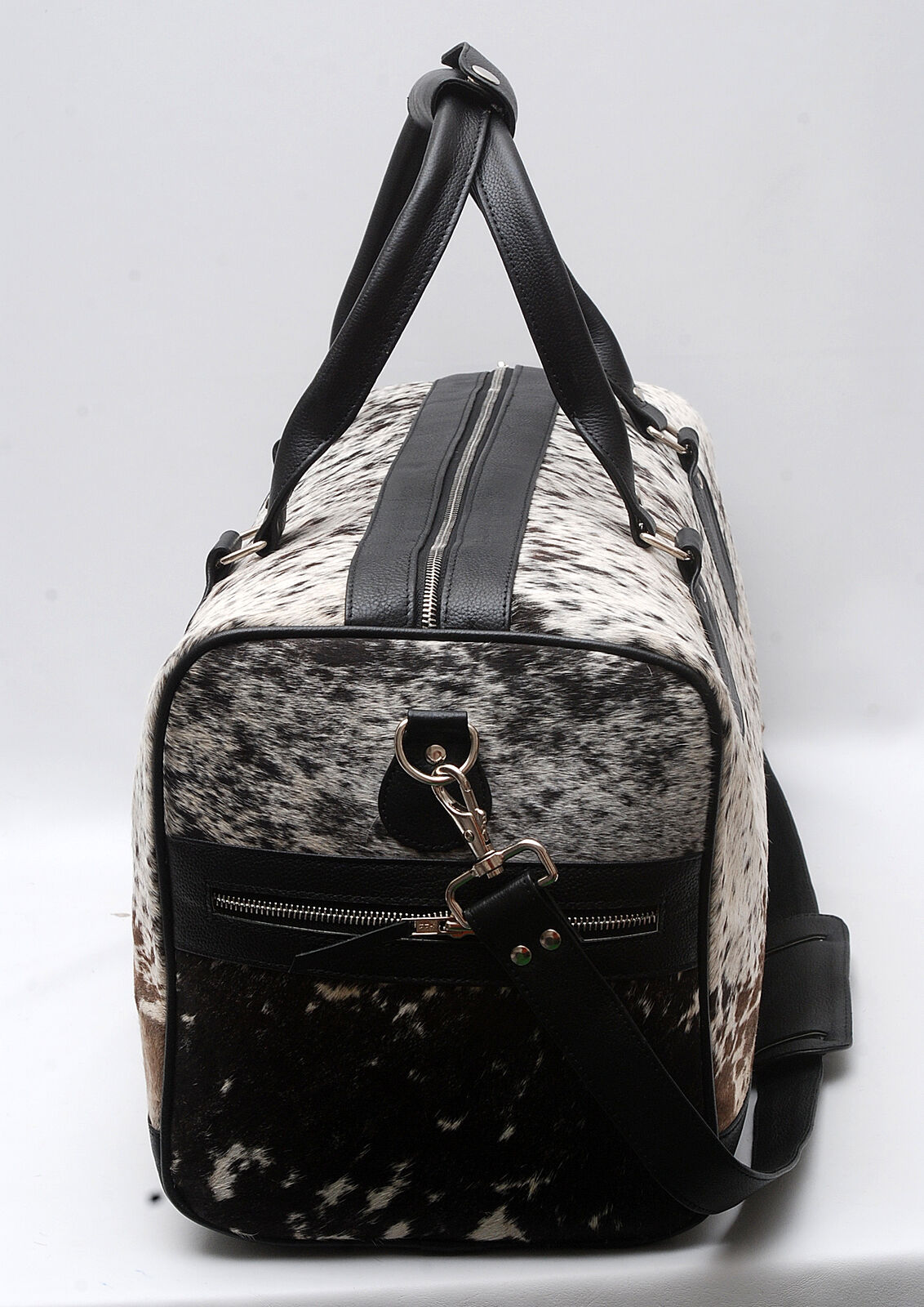 Embark on a journey of sophistication with this cow skin duffle bag, blending rugged charm with timeless luxury for the discerning traveler.