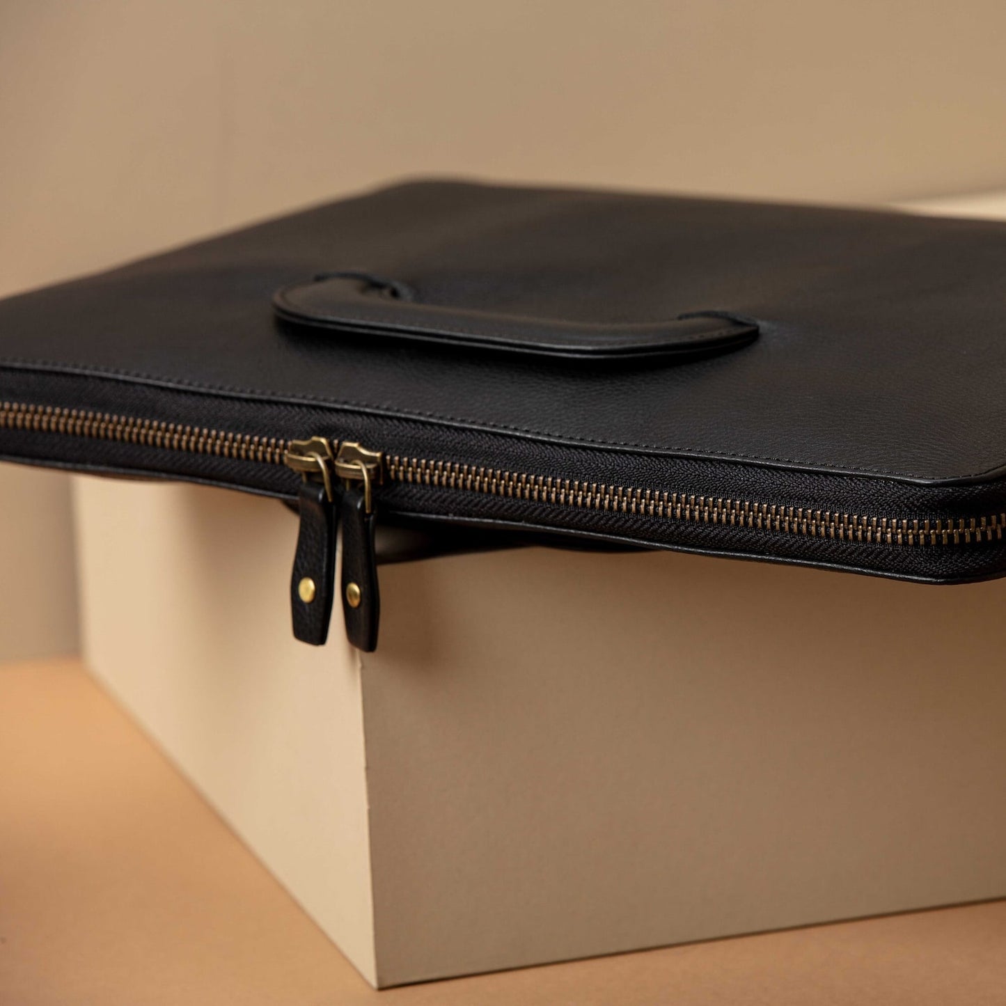 Professionelle Laptoptasche aus schwarzem Leder mit Reißverschluss, Griffen, und strukturierter Innenaufteilung für A4-Dokumente.