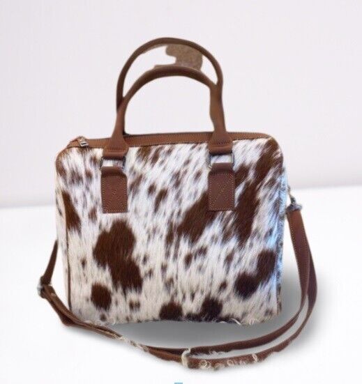 Elegant cowhide purse showcased on a rustic, sunlit bench.