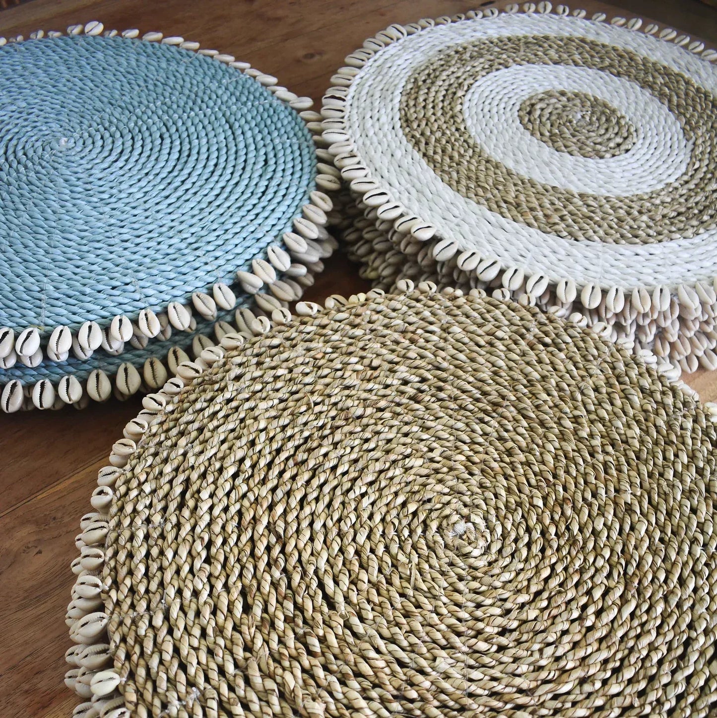 Set of dyed blue seagrass round placemats with cowrie shells