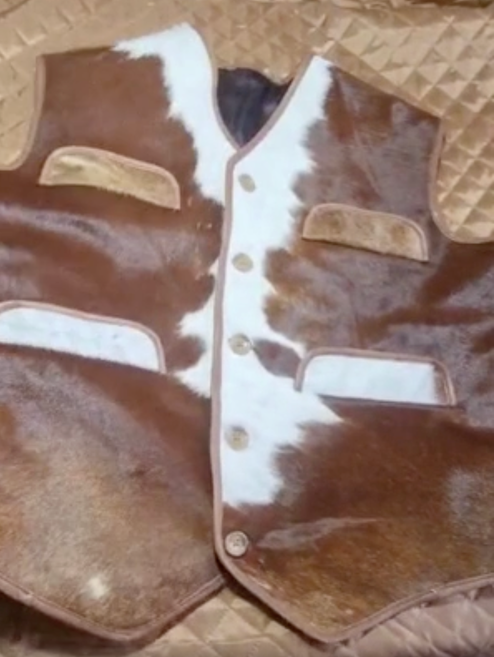 Western-style men’s cowhide vest made from real brown and white hide. Durable waistcoat jacket with pockets and button closure for rodeos, ranch life, and western outfits.