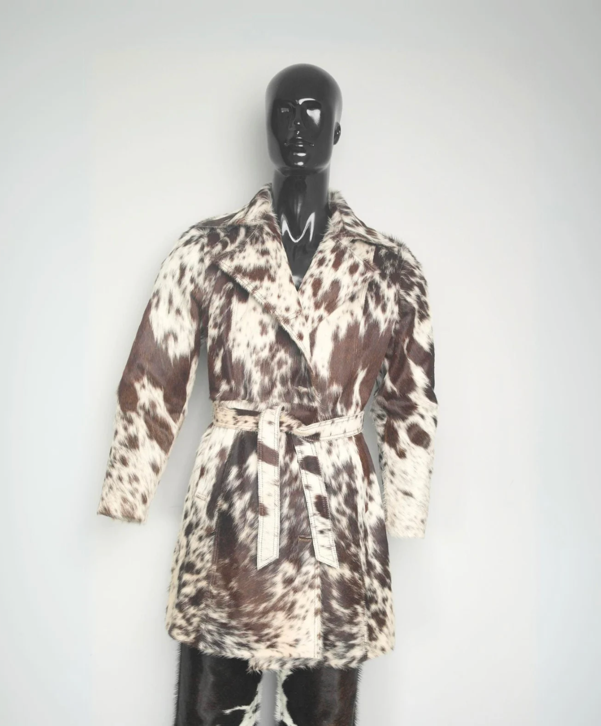 Women's brown and white cowhide trench coat made from real hair-on-hide leather with belted waist and tailored western silhouette.