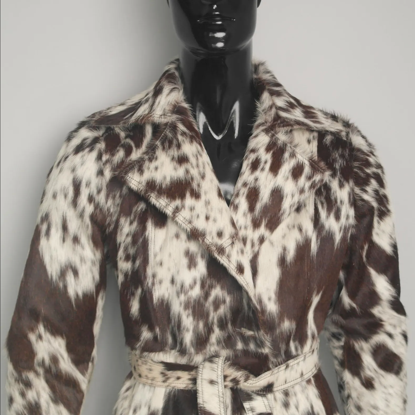Women's cowhide jacket in a trench style, featuring real hair-on-hide, belted waist, and unique natural color variations.