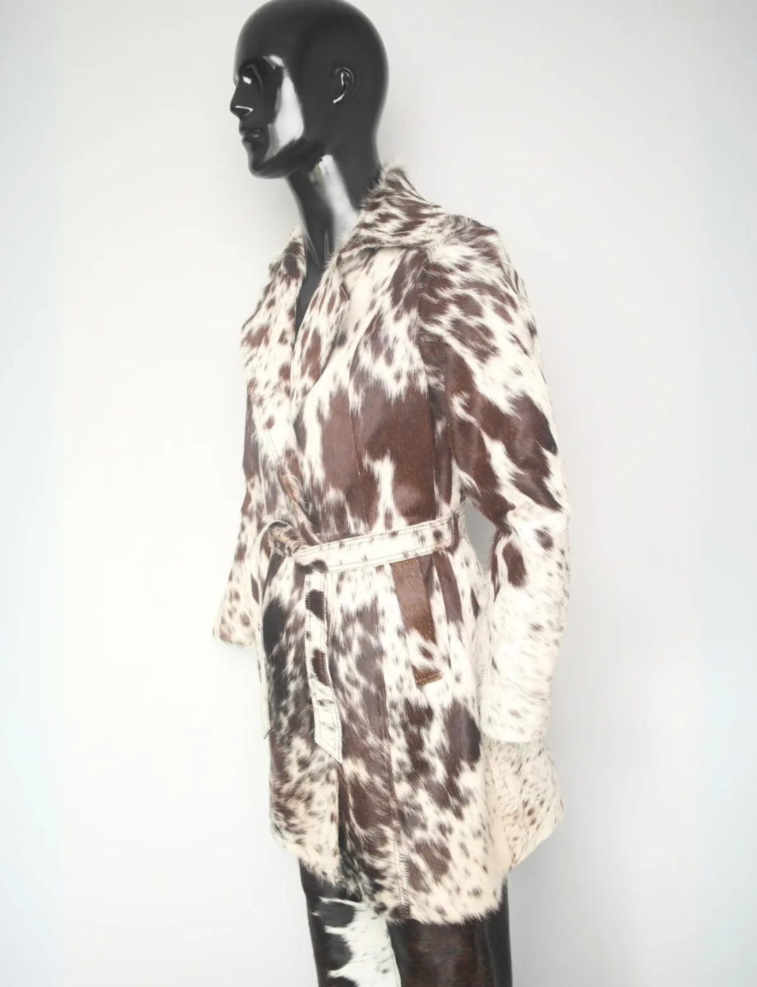 Authentic cow jacket for women in a long trench cut with bold brown and white cowhide pattern — limited edition outerwear.