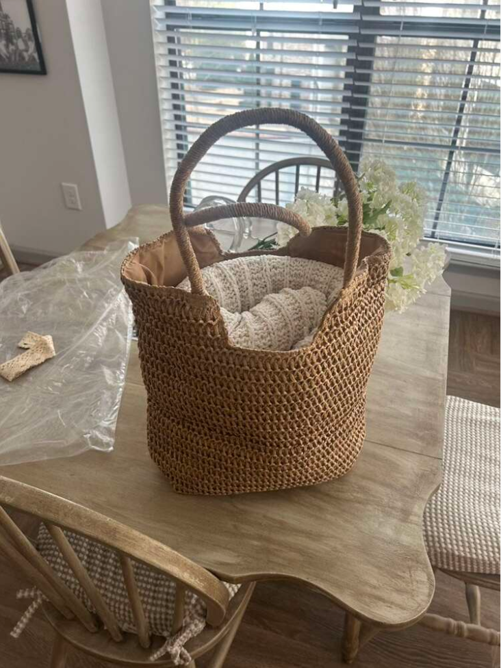 Crossbody beach bag resting on a driftwood log by the ocean