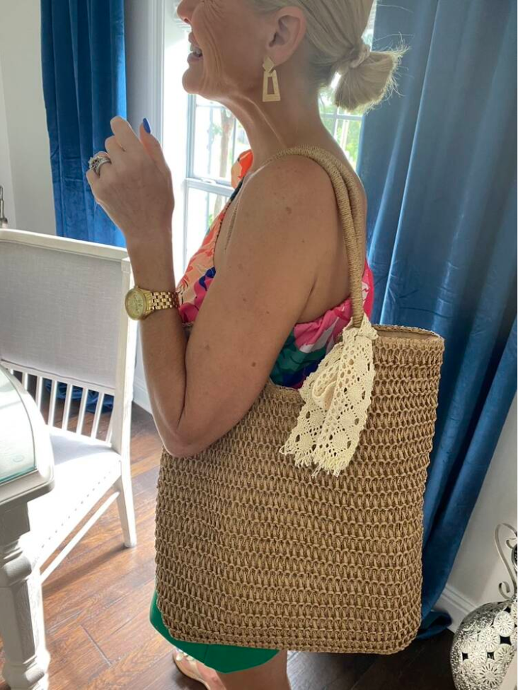 Small straw bag clipped onto a bicycle basket near a park path
