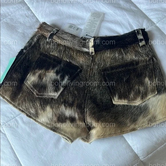 Real cow fur mini shorts featuring black, brown, and white tricolor hide. Designed for women seeking authentic cowhide fashion with a rugged edge.