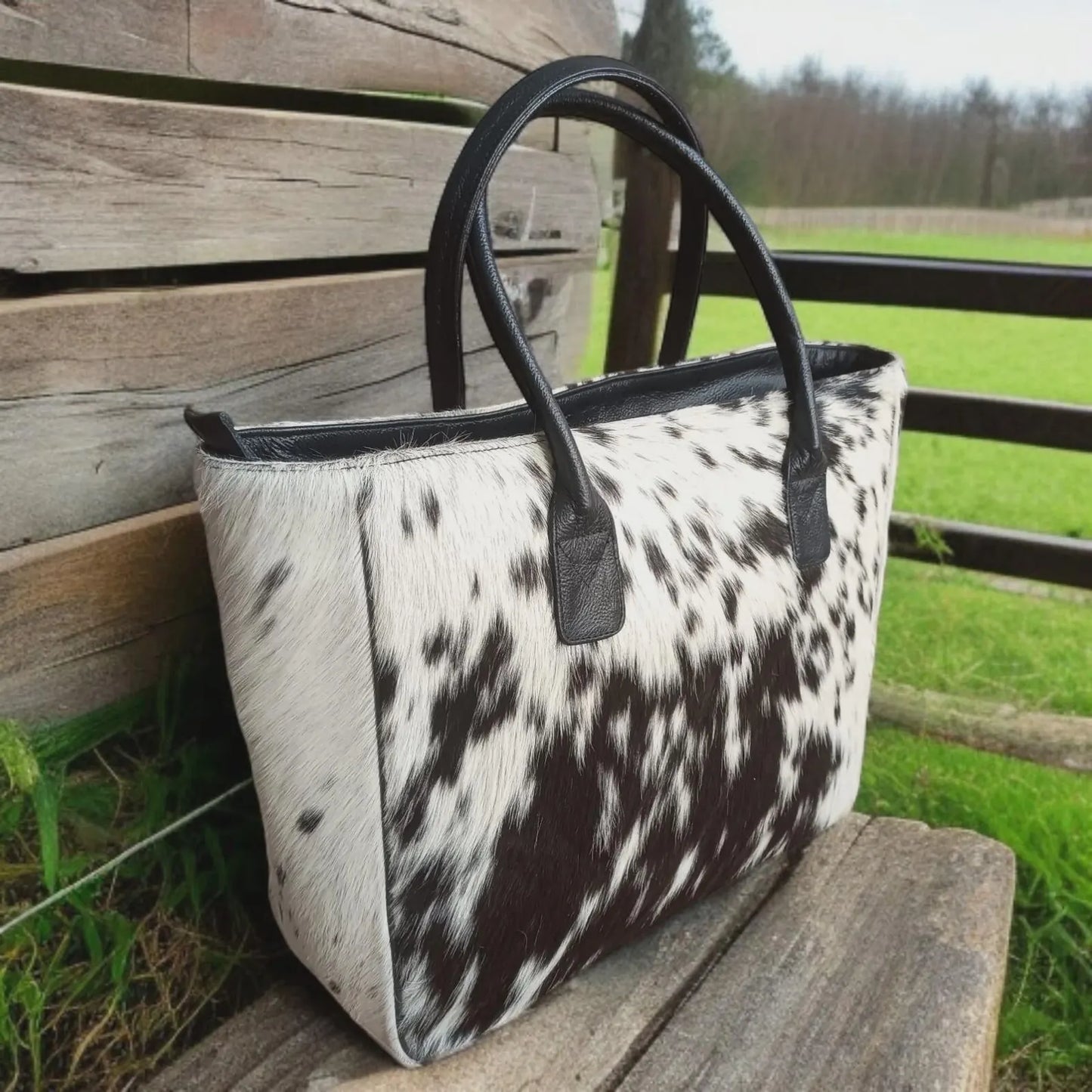 Handmade cowhide handbag with real hair-on leather, black and white spotted design, and a wide structured shape. Perfect western-style everyday bag.
