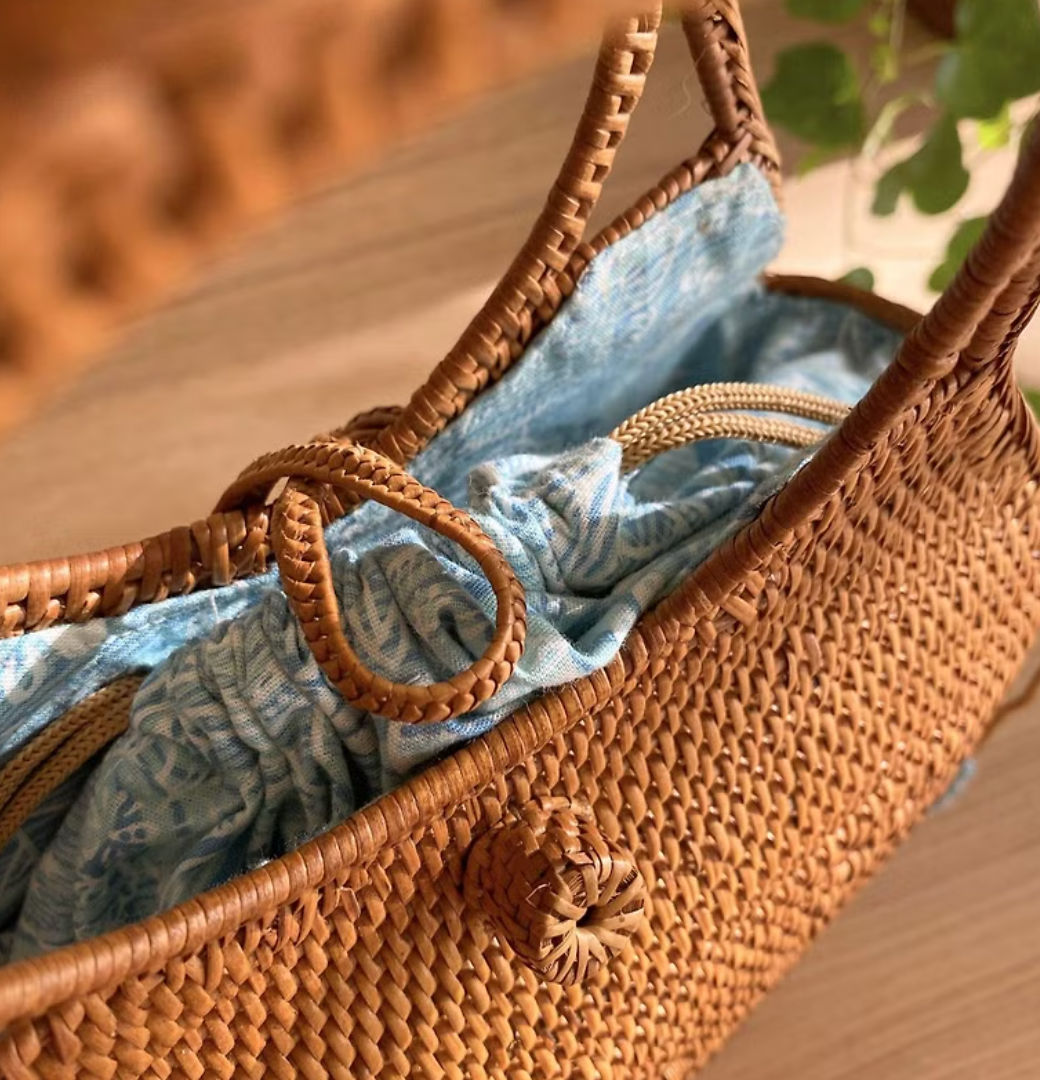 Unique square-shaped rattan clutch with colorful lining in sunlight.