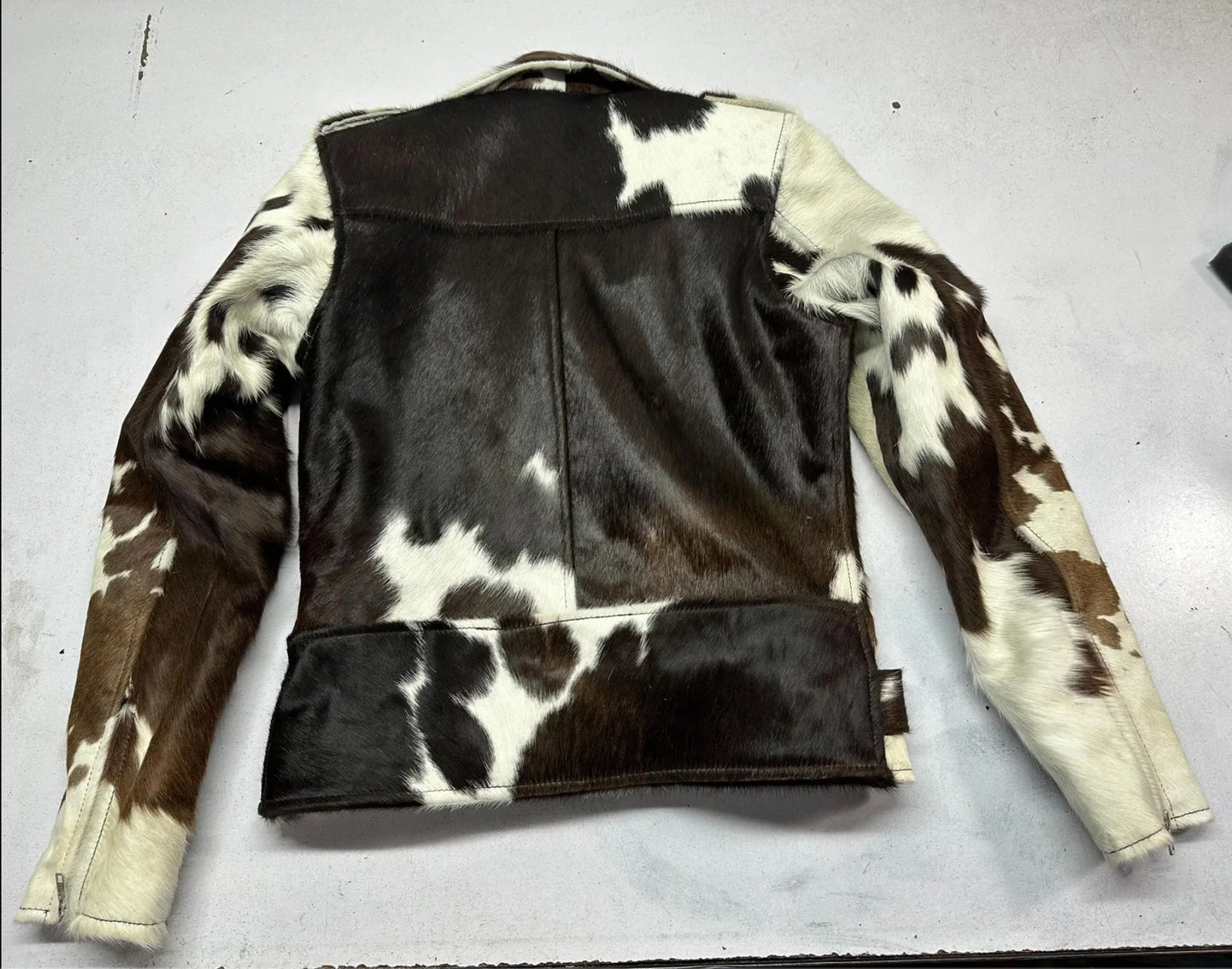 Western-style men’s cowhide fur coat with natural cow print hide, zip front, and adjustable belt. Real cowhide jacket mens option with raw edge finish.