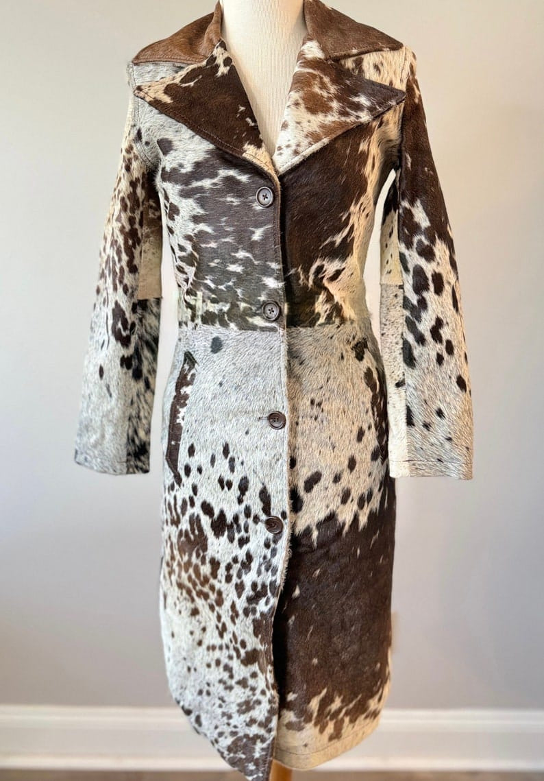 Long cowhide trench coat with natural fur texture. Women’s black, brown, white coat tailored for rodeo queens and country fashion.