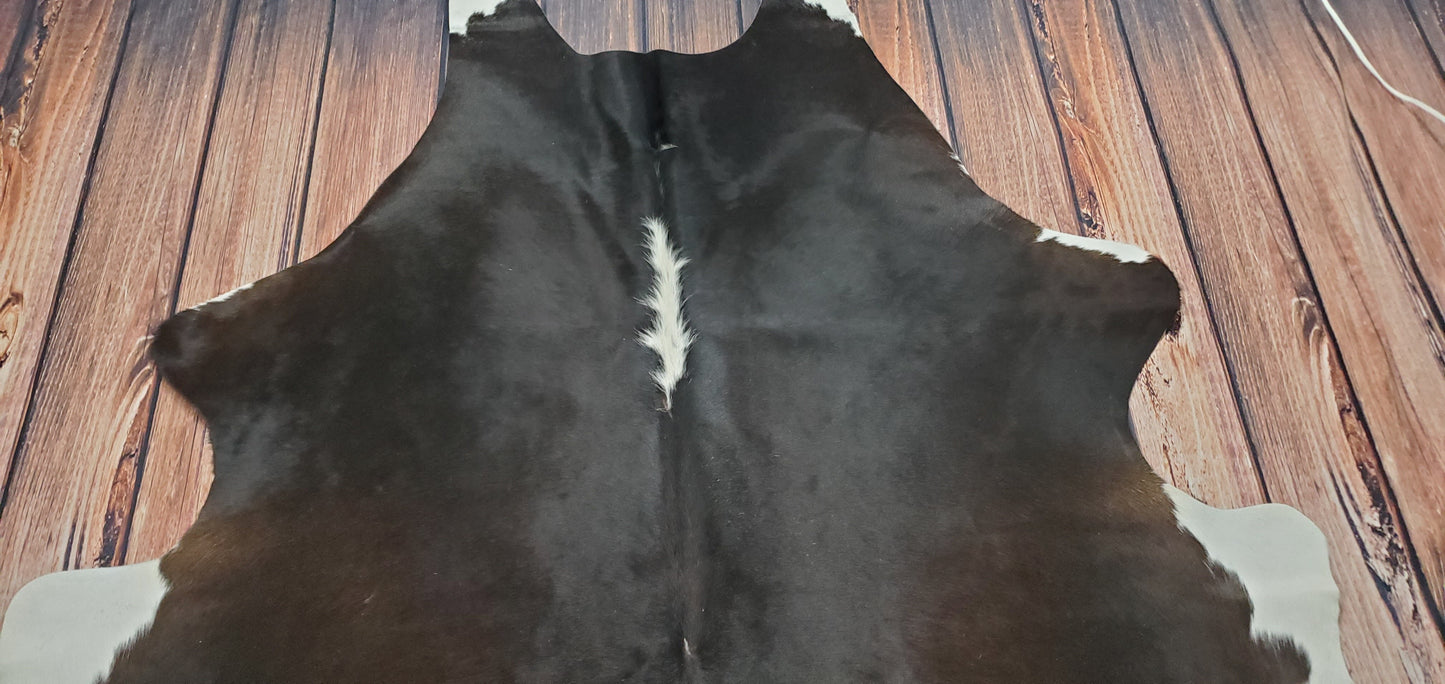 This dark brown black cowhide rug is perfect for creating a neutral space in your home. The rug's dark brown and black colors will complement any décor,