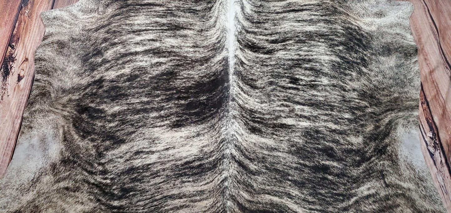 Detail shot of a soft and smooth-textured grey brindle cowhide rug, featuring natural patterns and a suede backing. The rug's fine finish and quality craftsmanship are highlighted.