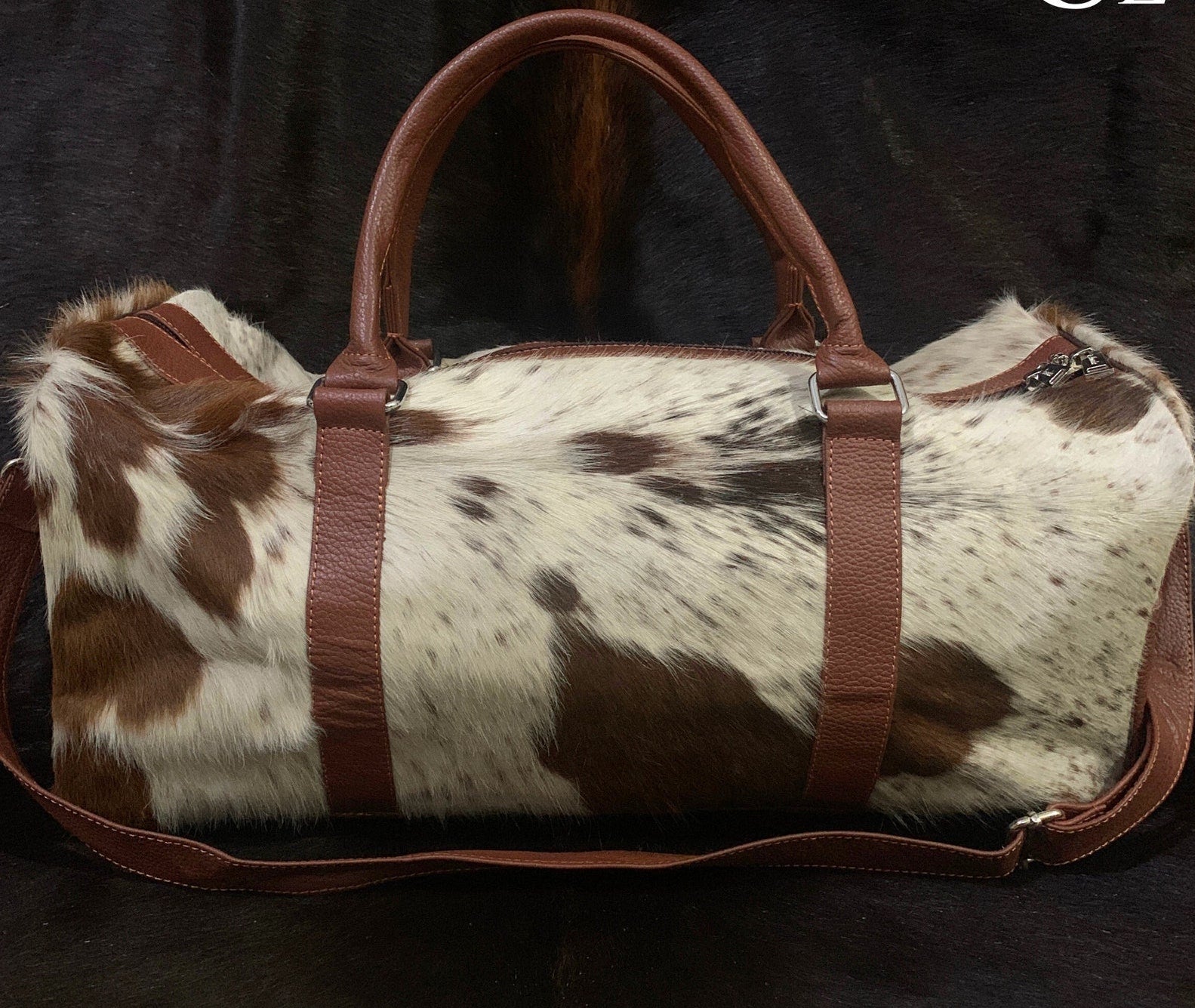 Unwind in style with this cowhide overnight bag, offering ample space for your essentials and more.
