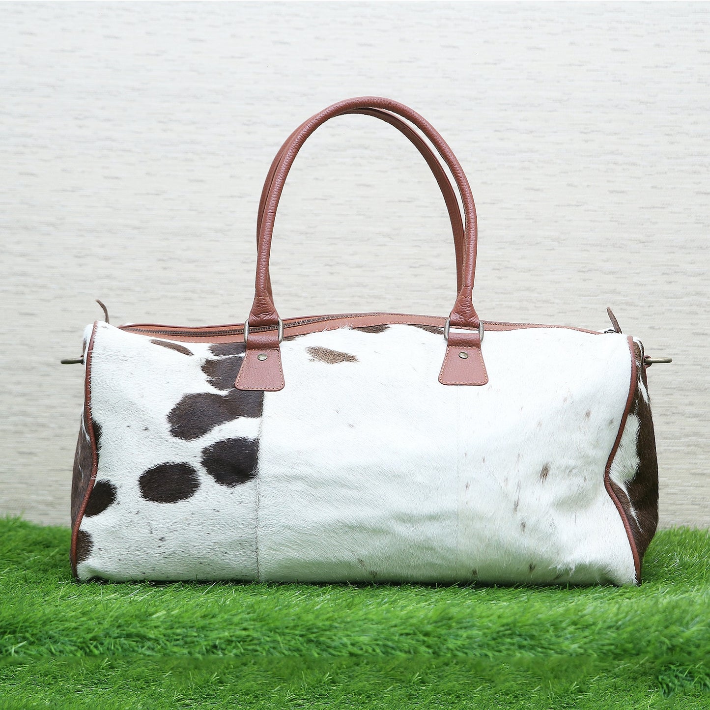 The inside of the cowhide luggage bag features two large compartments with plenty of room for packing clothes or other travel items. It also has an additional zippered pocket at the back which is ideal for storing valuables securely when out and about.