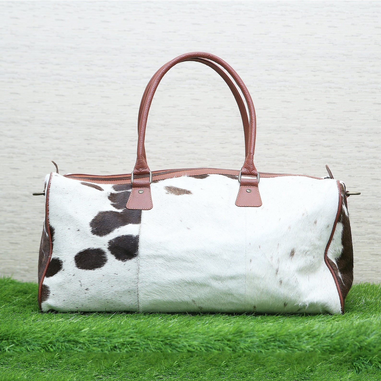 The inside of the cowhide luggage bag features two large compartments with plenty of room for packing clothes or other travel items. It also has an additional zippered pocket at the back which is ideal for storing valuables securely when out and about.
