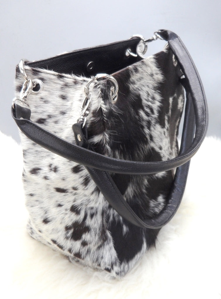A cowhide shoulder bag is a type of handbag that is typically worn with the strap over the shoulder and looks stunning with a fringe, made in black and white.