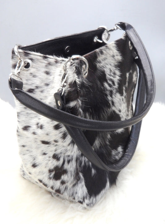 A cowhide shoulder bag is a type of handbag that is typically worn with the strap over the shoulder and looks stunning with a fringe, made in black and white.