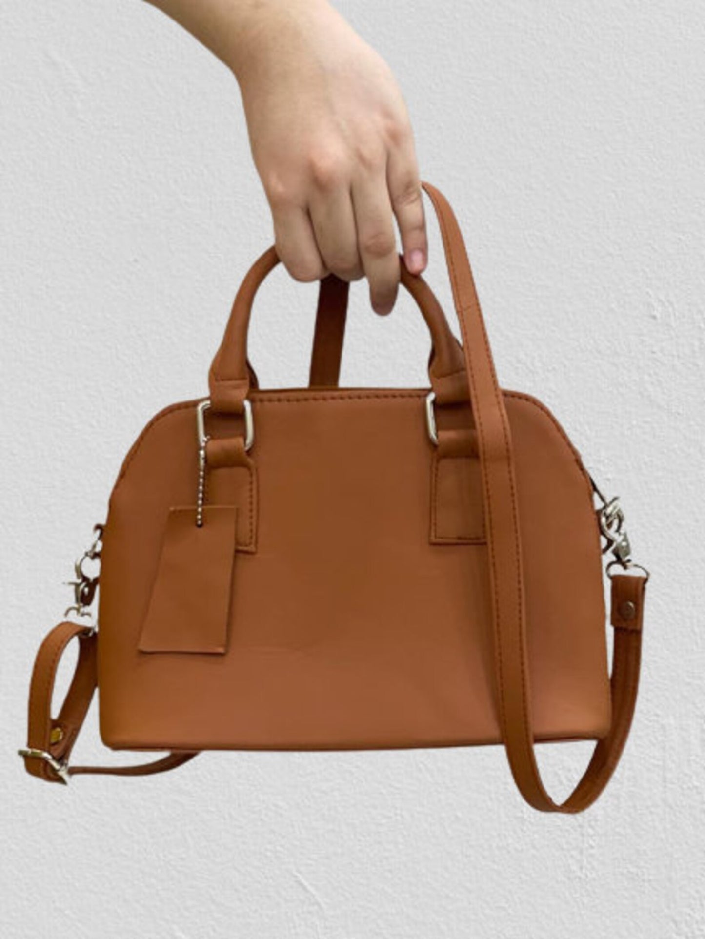 Real leather crossbody bag with subtle stitching, styled next to matching accessories.