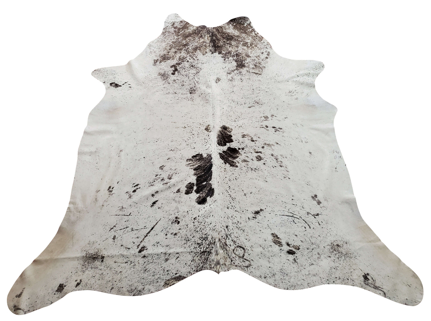 In the living room of a farmhouse, a nice grey white cowhide rug with a cozy throw and a fireplace can add elegance to any space.