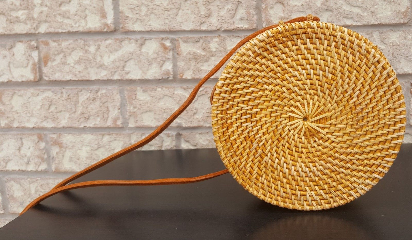 Modern rattan bag on a sandy beach with seashell accents, evoking a tropical and relaxed feel.