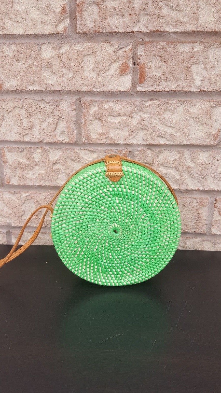 Handcrafted rattan crossbody bag with a circular design and secure clasp.
