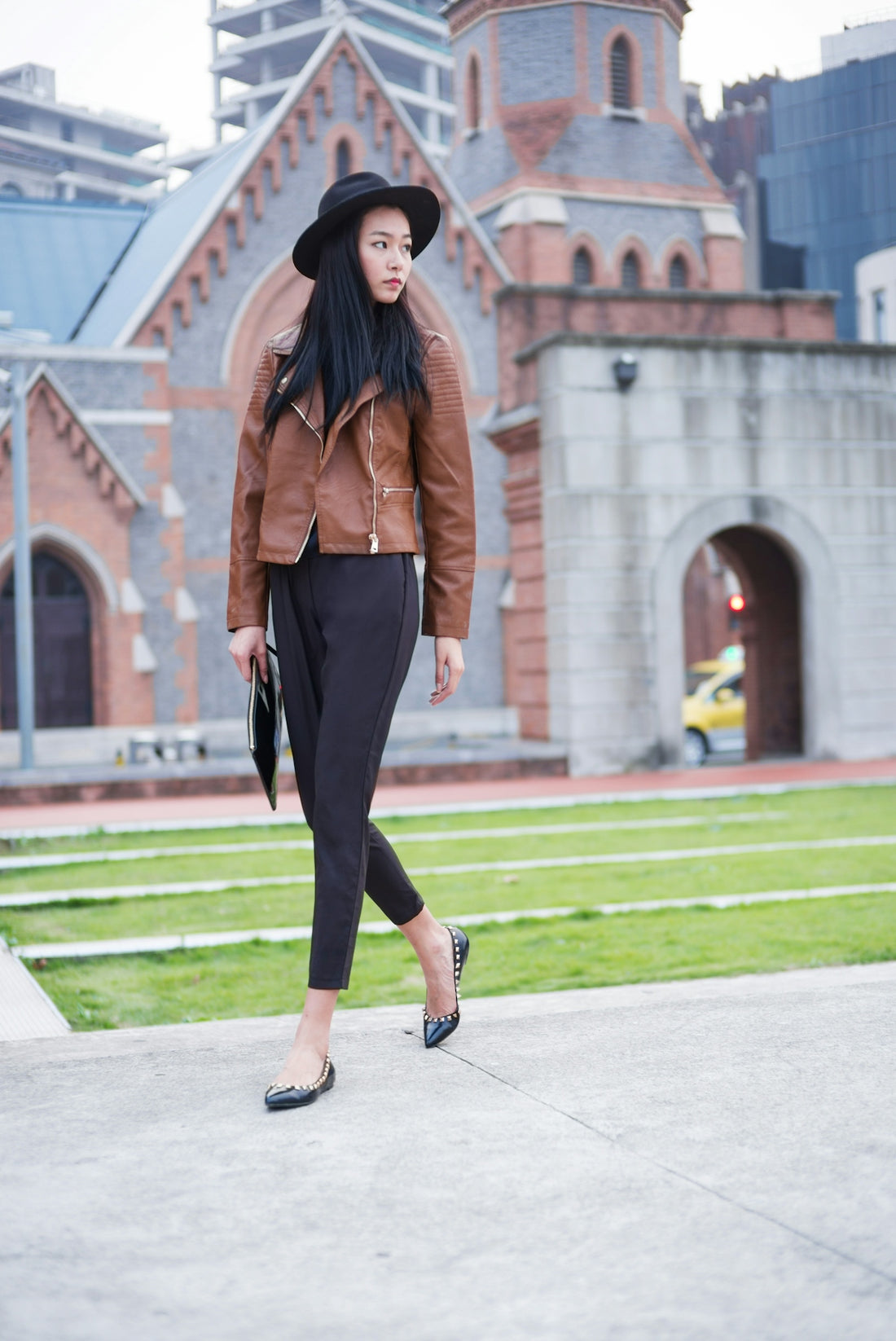woman in brown jacket and black pants standing on gray concrete pavement during daytime