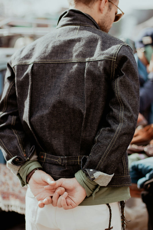 a man wearing a jean jacket and white pants