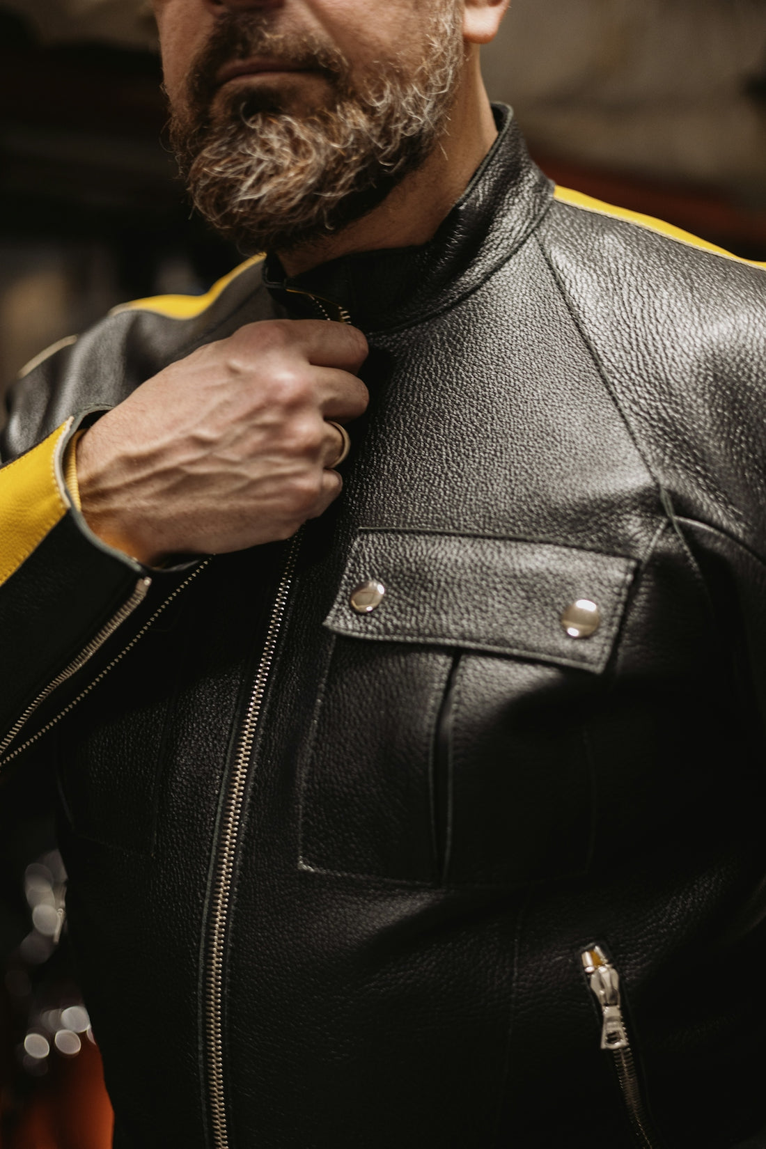 a man in a leather jacket adjusts his tie