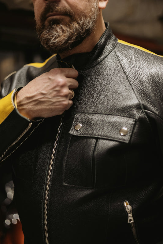 a man in a leather jacket adjusts his tie