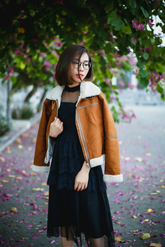 a woman in a black dress and a brown jacket