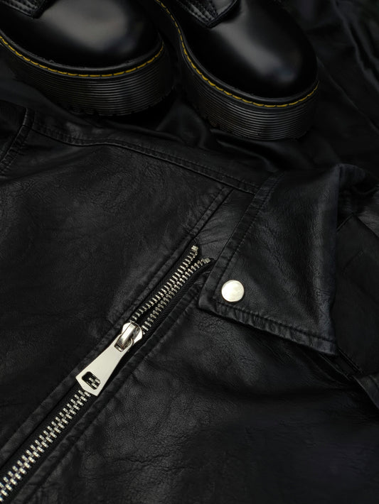 A pair of black shoes sitting on top of a black leather jacket