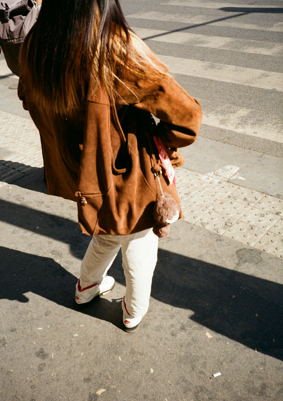 Woman in brown jacket crossing street on crosswalk