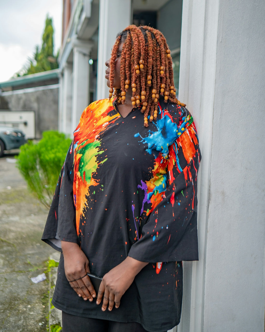 Woman with colorful paint splatter shirt and beaded hair