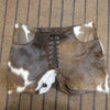Front lace cowhide leather shorts in brown and white pattern. Perfect for rodeo events, country music festivals, and standout cowgirl outfit inspiration.

