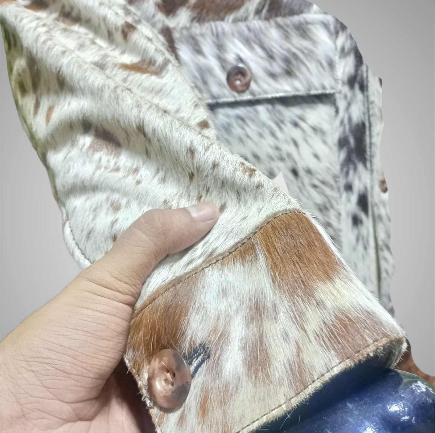 Tricolor cowhide fur coat with button-up front and natural pattern. Real cow skin jacket for men featuring patch pockets and rodeo-ready cow print hide detail.

