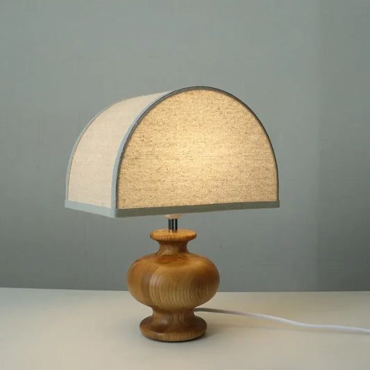 Ash wood table lamp with rounded base and softly curved fabric dome shade.