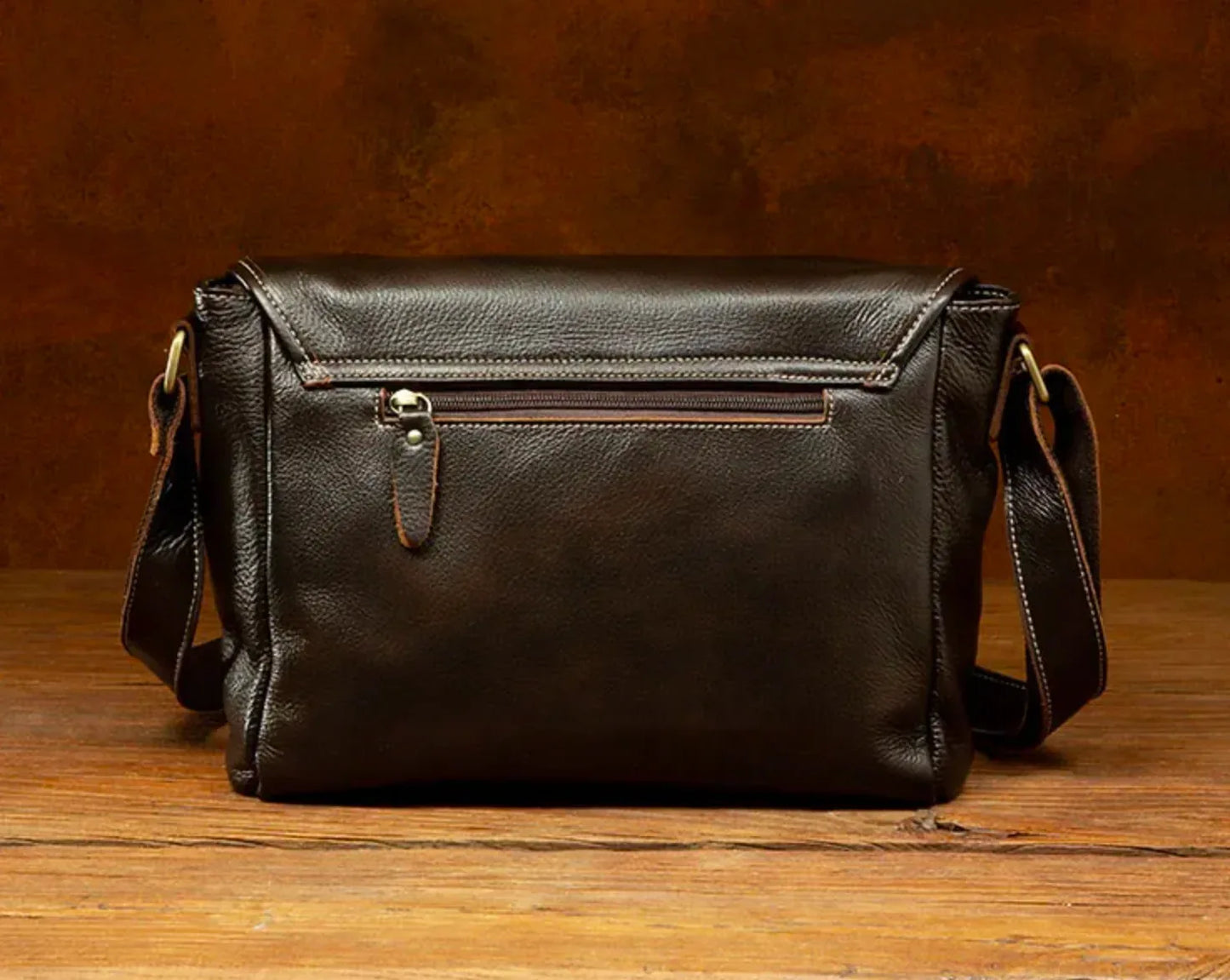 Brown leather crossbody satchel shown from the bottom with structured rectangular base and natural leather grain.
