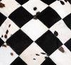 Cowhide patchwork pillow cover featuring geometric black white diamonds, genuine hair-on hide texture, and natural pattern variation.