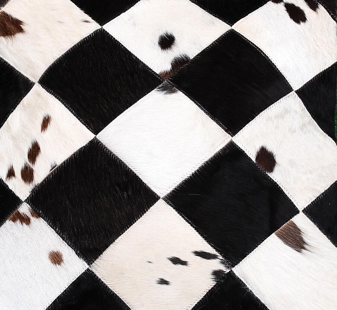 Cowhide patchwork pillow cover featuring geometric black white diamonds, genuine hair-on hide texture, and natural pattern variation.