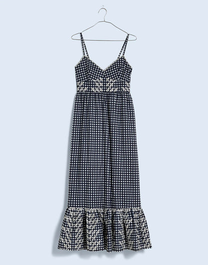  Gingham maxi dress with side pockets, a floral motif waist band, and a contrasting patterned ruffle hem.