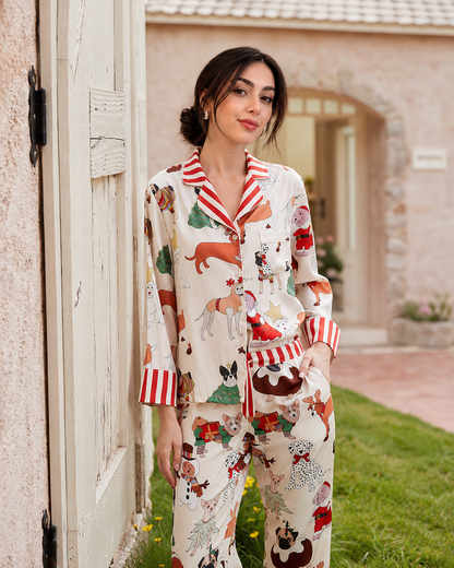 A woman wearing a two-piece pajama set with a festive Christmas dog print, standing outdoors next to a rustic white door.
