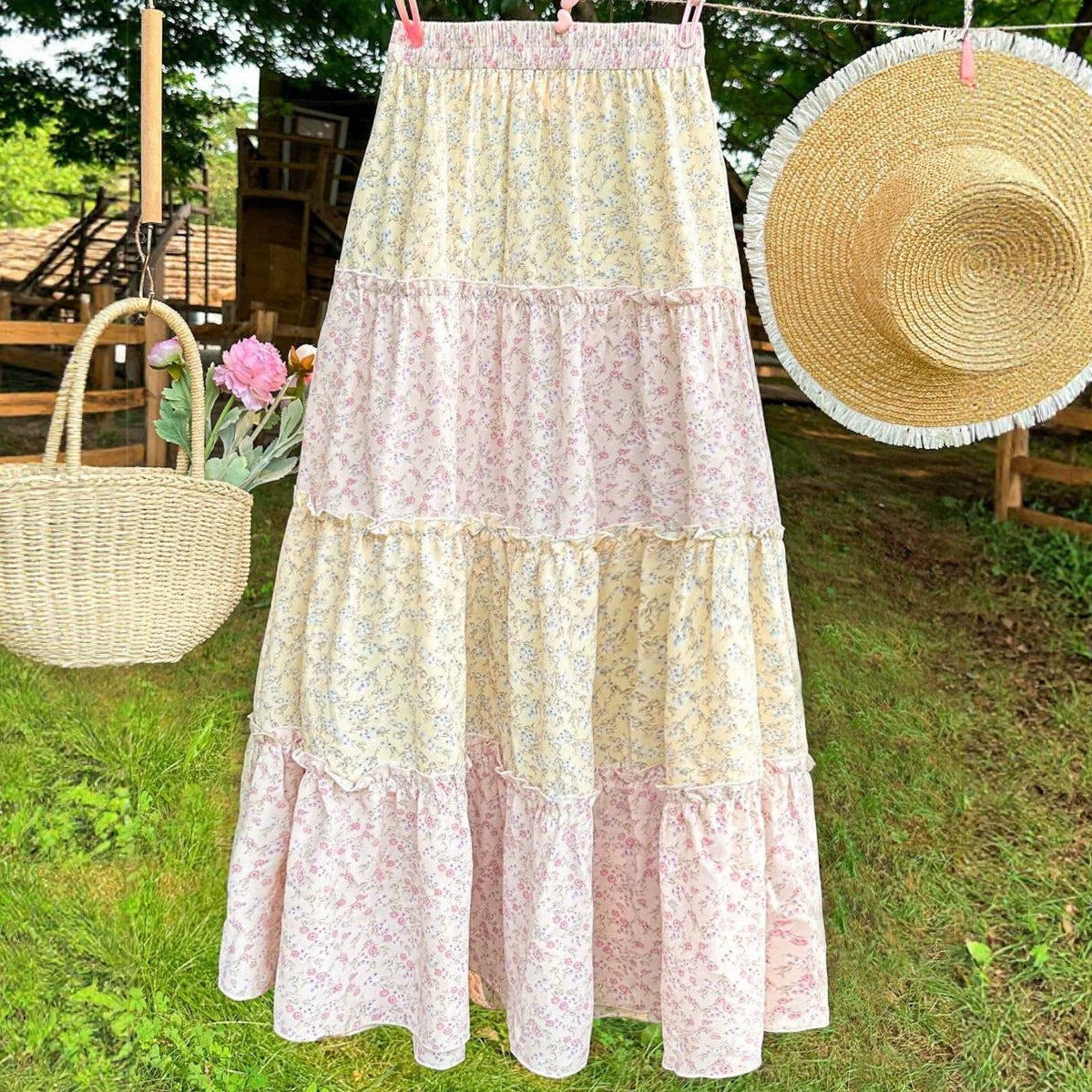 Maxi skirt with pink and yellow floral tiers and flowing A-line shape.