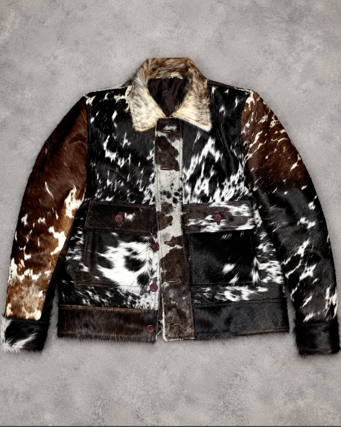 Men’s cowhide jacket featuring black, brown, cream, and white hair-on hide with pointed collar and western influence.