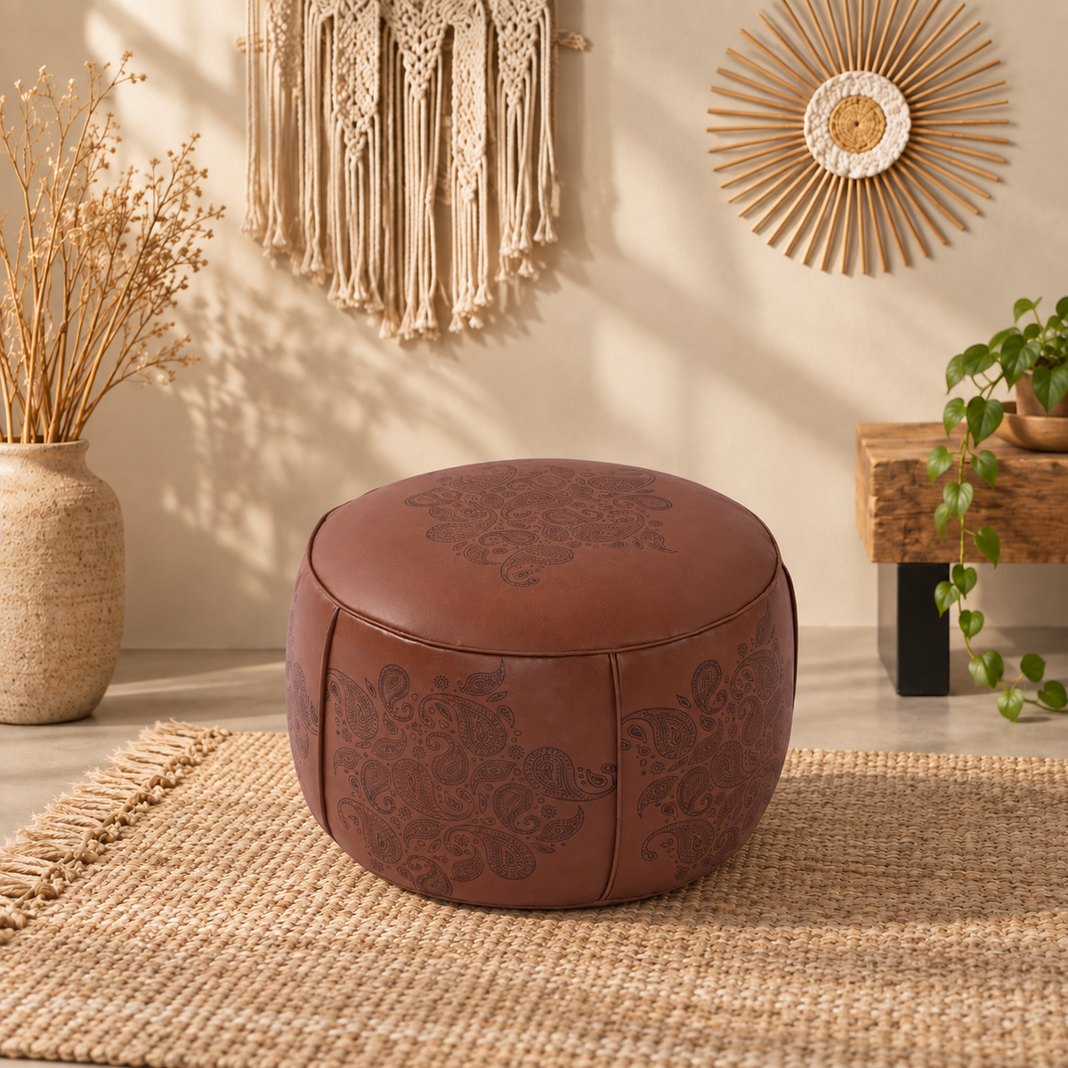 Round faux leather pouf ottoman with decorative Moroccan pattern, tan surface, and rounded silhouette for casual floor seating.