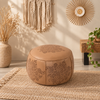Round faux leather pouf ottoman featuring vintage embossed motifs and warm earthy tones for layered living room decor.
