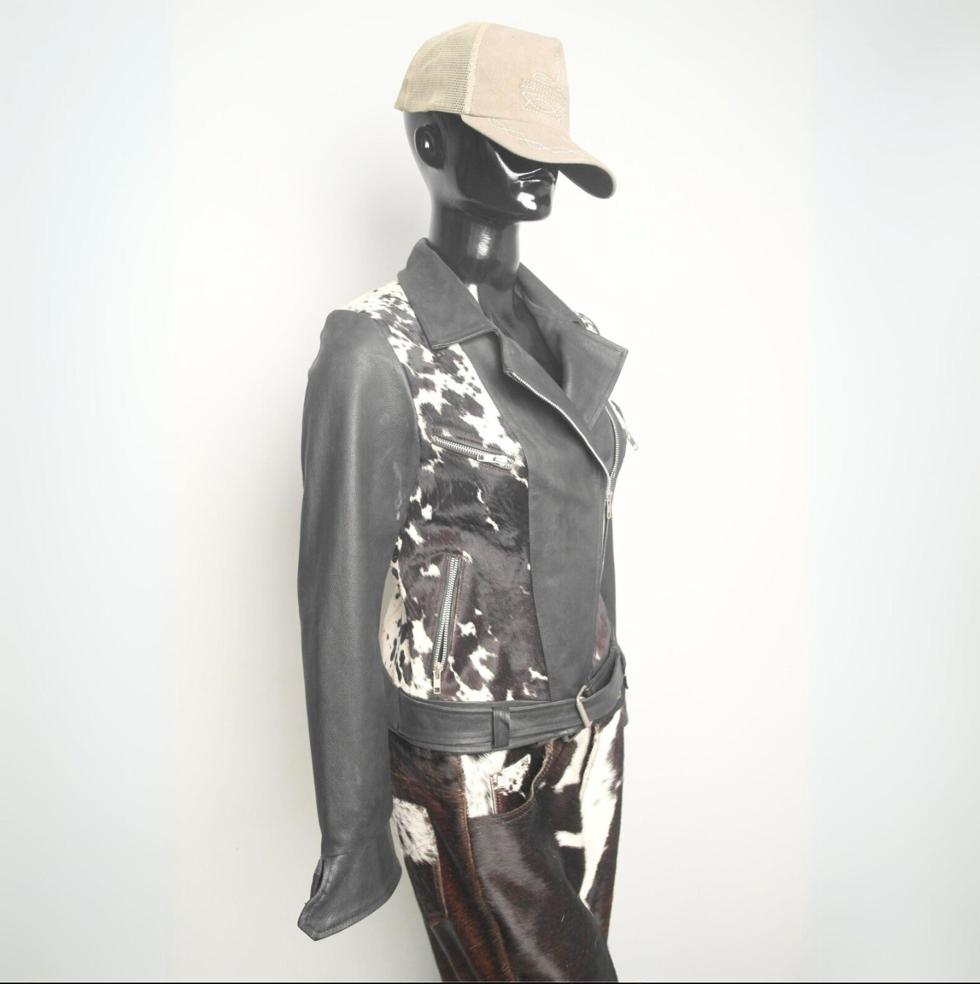Black and white cowhide leather jacket for women with a belted waist, unique cow print, and bold western influence.

