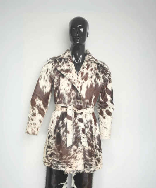 Women's brown and white cowhide trench coat made from real hair-on-hide leather with belted waist and tailored western silhouette.
