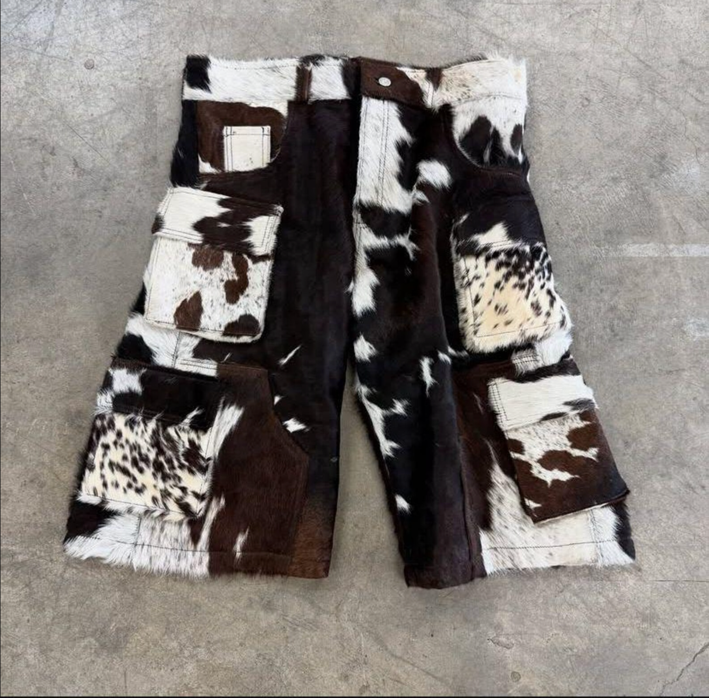 Western-inspirierte Kuhfell-Cargoshorts aus echtem Leder, mit einzigartigem Muster, Knopfverschluss und Seitentaschen. Markanter Stil für kreative Outfits.

